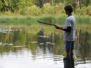 Evening light weaves its magic around the river as Gavin angles for fish with his make-shift rod, and fishes for leeches with his toes in the muck. These kids may not have hooked a fish, but the river hooked them. Photo by Emily Stone.